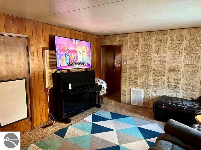 carpeted living room featuring wooden walls