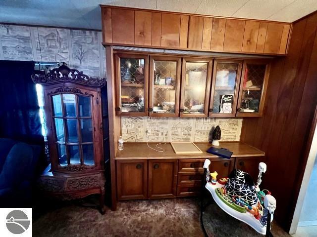 bar featuring wood walls, built in desk, and dark colored carpet