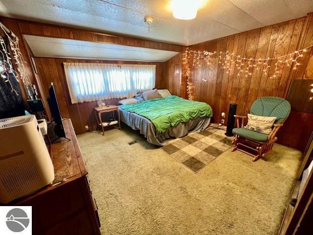 carpeted bedroom featuring wood walls