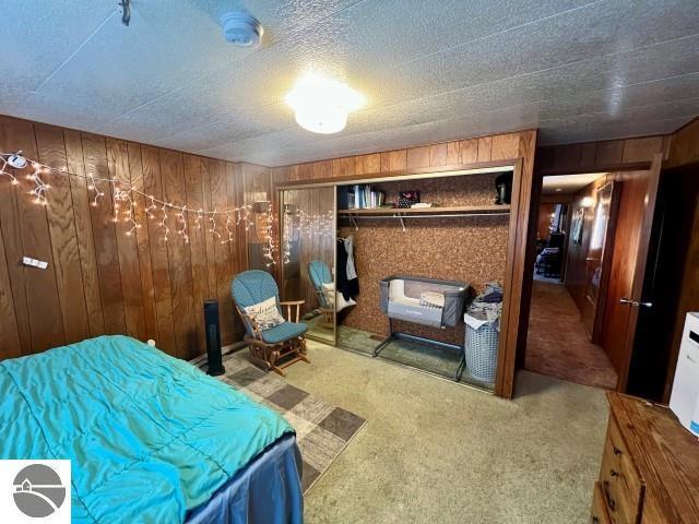 bedroom with carpet flooring, a closet, and wooden walls