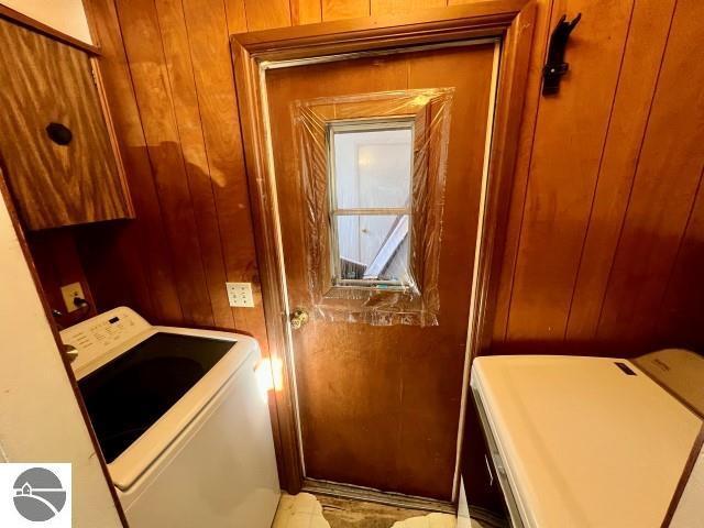 laundry room featuring washer and clothes dryer and wood walls