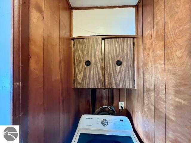 laundry room featuring cabinets, washer / dryer, and wood walls