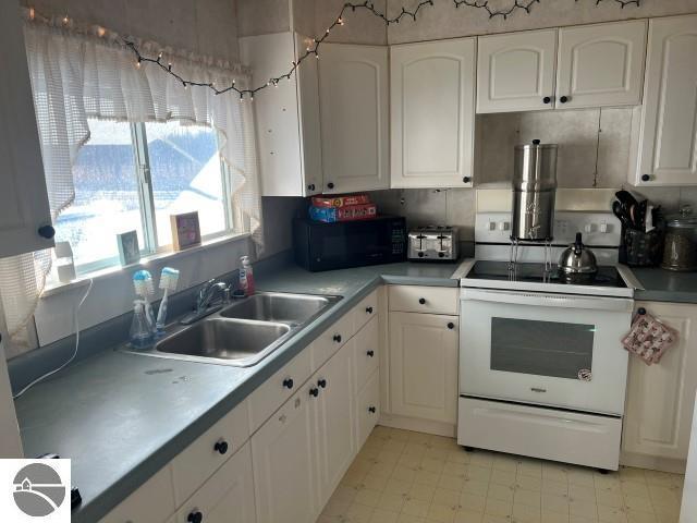 kitchen with sink, white cabinetry, and electric stove