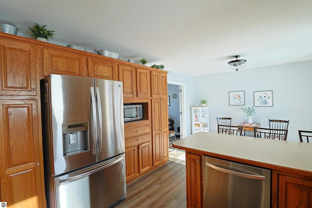 kitchen with hardwood / wood-style floors, appliances with stainless steel finishes, and a textured ceiling