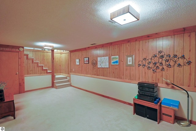 basement with a textured ceiling, wooden walls, and carpet floors