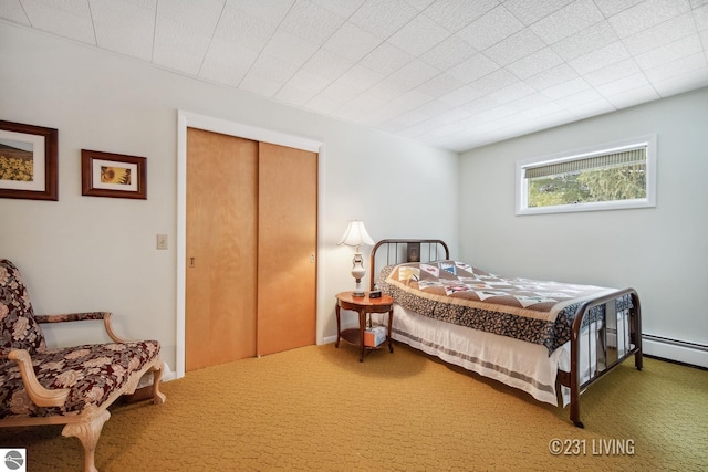 bedroom featuring baseboard heating, a closet, and carpet