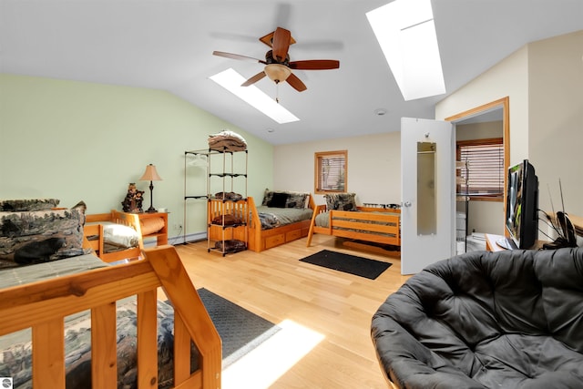 bedroom featuring ceiling fan, a baseboard radiator, hardwood / wood-style flooring, and vaulted ceiling with skylight