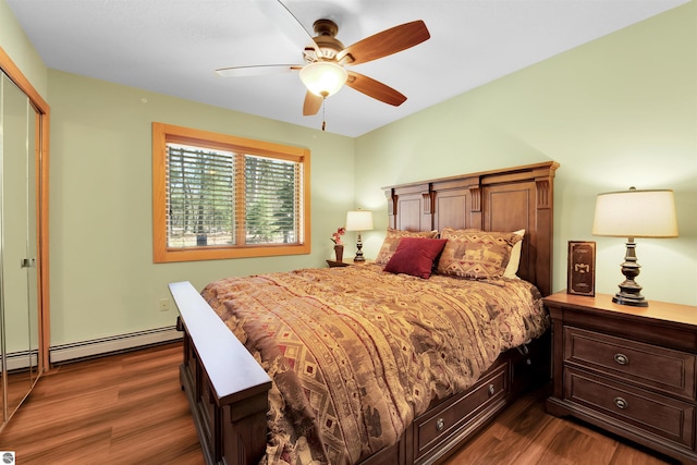 bedroom featuring dark wood-type flooring, a closet, a baseboard heating unit, and ceiling fan