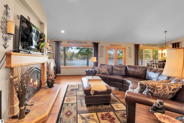 living room featuring a tile fireplace, light hardwood / wood-style floors, a baseboard heating unit, and a wealth of natural light