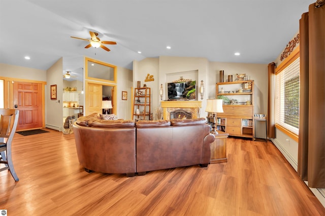 living room featuring ceiling fan, a baseboard heating unit, lofted ceiling, and light wood-type flooring