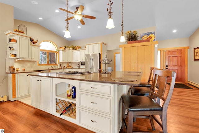 kitchen with tasteful backsplash, a kitchen island, pendant lighting, stainless steel appliances, and lofted ceiling