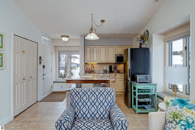 kitchen featuring hanging light fixtures, backsplash, light stone countertops, and light tile patterned flooring