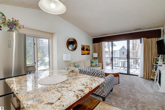 carpeted dining space with vaulted ceiling