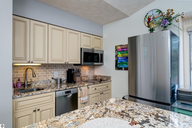 kitchen with cream cabinets, backsplash, a textured ceiling, and appliances with stainless steel finishes