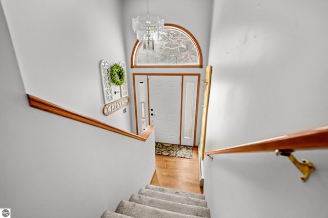 foyer entrance featuring an inviting chandelier, a towering ceiling, and hardwood / wood-style floors