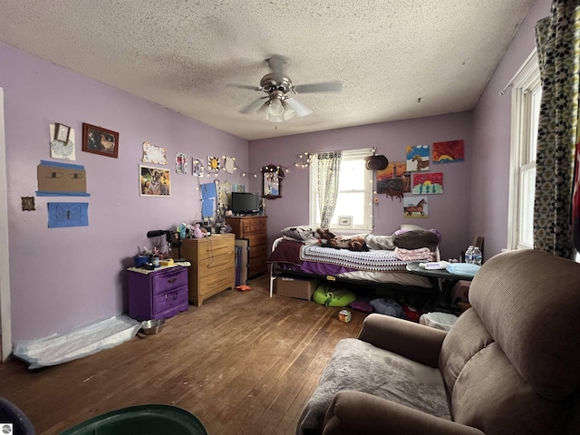 bedroom with wood-type flooring, a textured ceiling, and ceiling fan