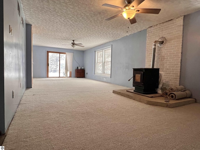 carpeted living room with ceiling fan, a textured ceiling, and a wood stove