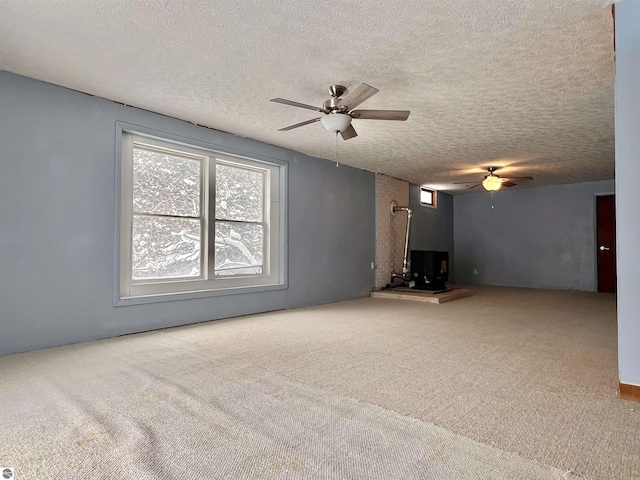 unfurnished living room with ceiling fan, carpet floors, and a textured ceiling