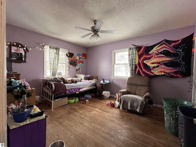 bedroom with hardwood / wood-style flooring, ceiling fan, multiple windows, and a textured ceiling