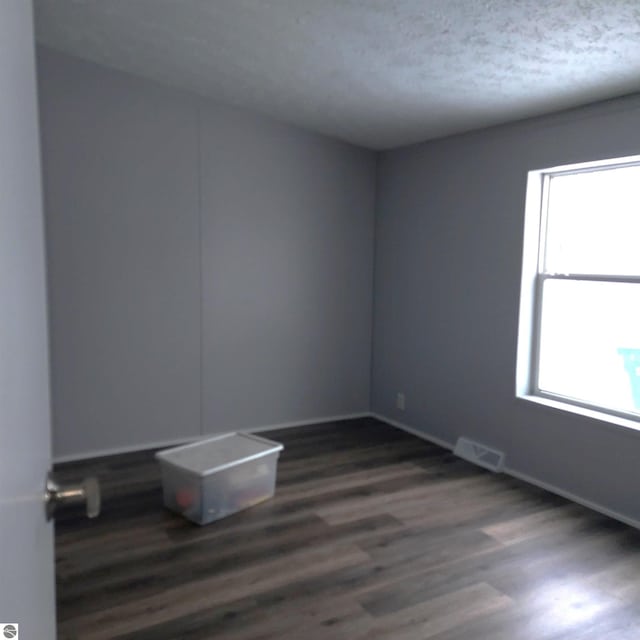 unfurnished room with dark hardwood / wood-style floors and a textured ceiling