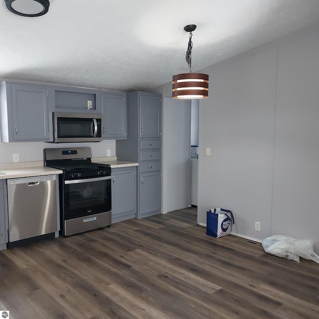 kitchen with decorative light fixtures, dark wood-type flooring, and stainless steel appliances