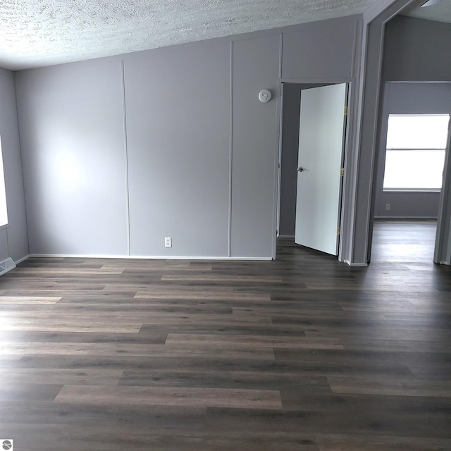 spare room with dark hardwood / wood-style flooring and a textured ceiling