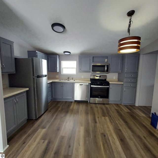 kitchen with dark wood-style floors, gray cabinets, stainless steel appliances, and light countertops