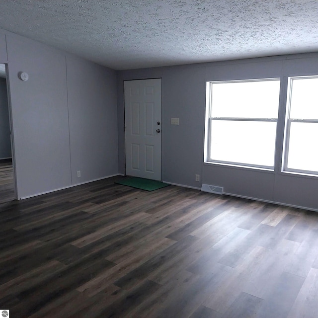 spare room with dark wood-type flooring and a textured ceiling