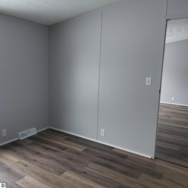 empty room with dark wood-type flooring and a textured ceiling