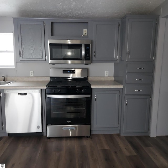 kitchen featuring gray cabinets, dark hardwood / wood-style flooring, appliances with stainless steel finishes, and a textured ceiling