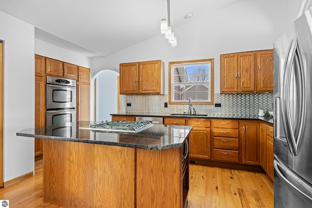 kitchen with lofted ceiling, sink, a center island, pendant lighting, and stainless steel appliances