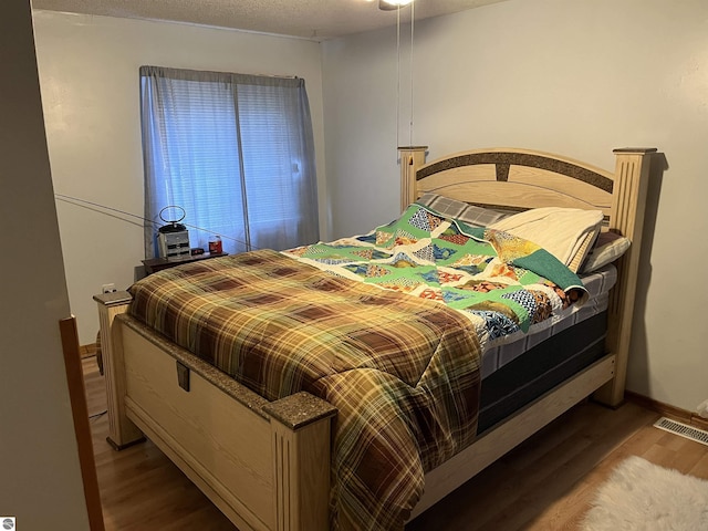 bedroom with hardwood / wood-style floors and a textured ceiling