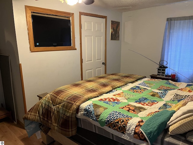 bedroom featuring ceiling fan, hardwood / wood-style floors, and a textured ceiling