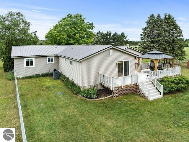 rear view of property featuring a gazebo, a yard, a wooden deck, and central air condition unit