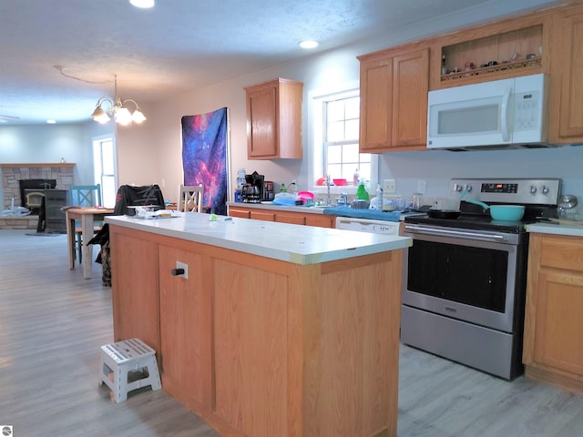 kitchen featuring pendant lighting, stainless steel range with electric cooktop, a center island, a notable chandelier, and light wood-type flooring