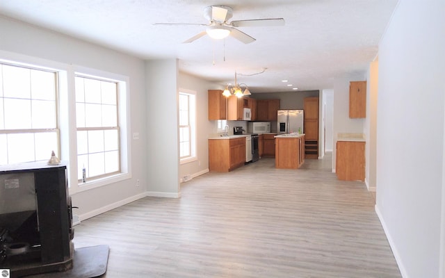 kitchen featuring hanging light fixtures, a center island, ceiling fan, stainless steel appliances, and light wood-type flooring