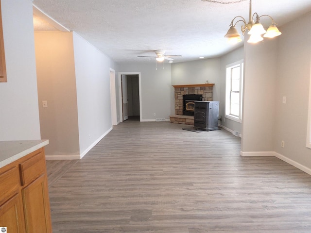 unfurnished living room with ceiling fan with notable chandelier, light hardwood / wood-style flooring, and a textured ceiling