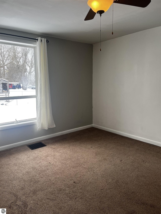 empty room featuring carpet, a wealth of natural light, and ceiling fan