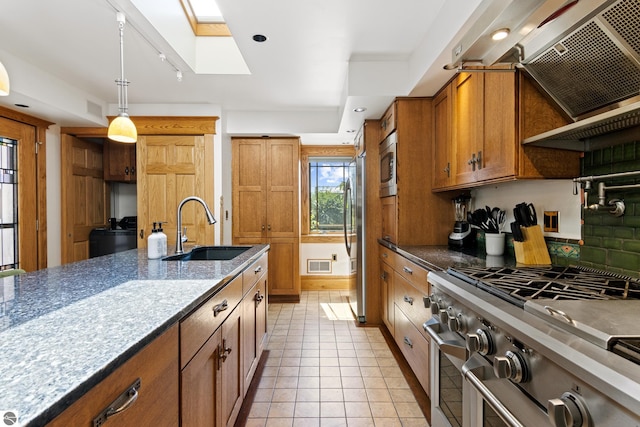 kitchen with range hood, a skylight, sink, hanging light fixtures, and stainless steel appliances