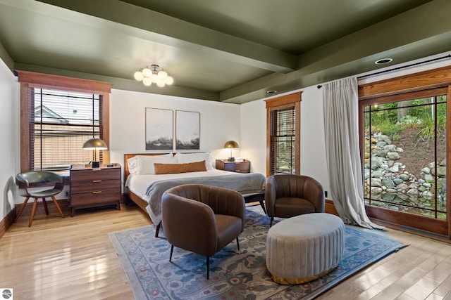 bedroom featuring an inviting chandelier, multiple windows, and light wood-type flooring