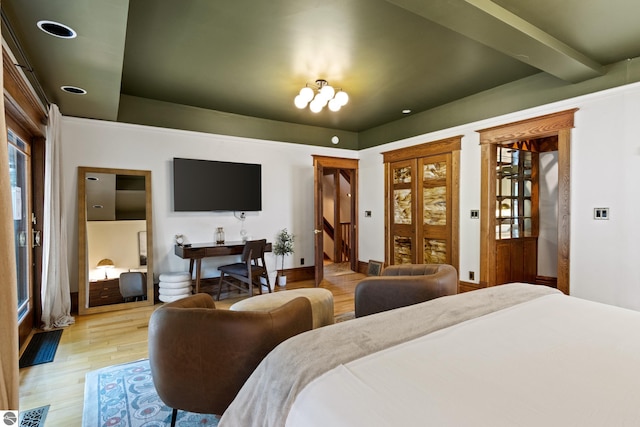 bedroom featuring beamed ceiling, an inviting chandelier, and light hardwood / wood-style floors