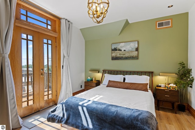 bedroom with light hardwood / wood-style flooring, access to outside, french doors, and an inviting chandelier