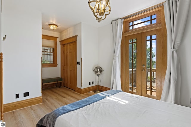 bedroom featuring a notable chandelier, access to exterior, light hardwood / wood-style floors, and french doors