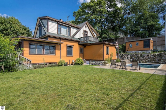 back of house featuring a balcony, a lawn, and a patio area