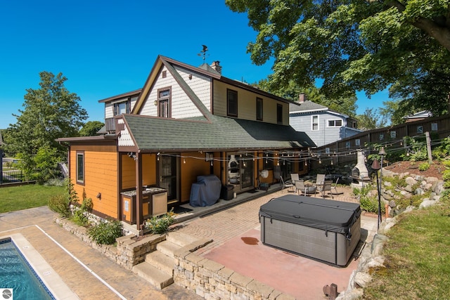 back of house with a swimming pool with hot tub and a patio area