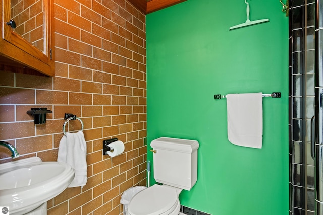 bathroom with brick wall, sink, and toilet