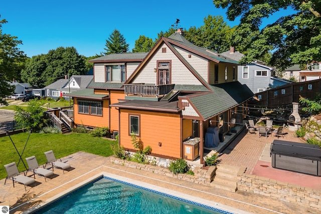 rear view of house featuring a patio, a balcony, and a yard