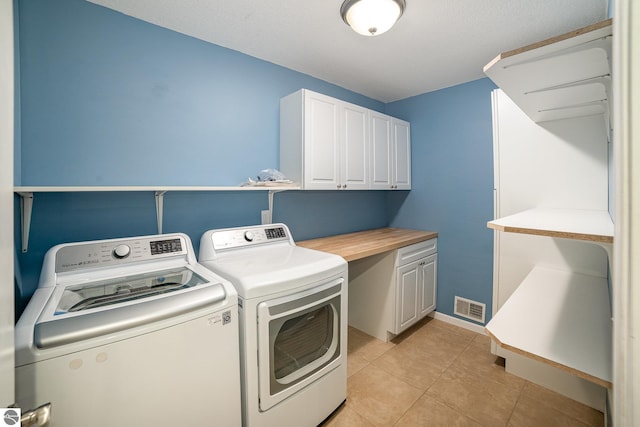 clothes washing area featuring light tile patterned flooring, cabinets, and washing machine and dryer