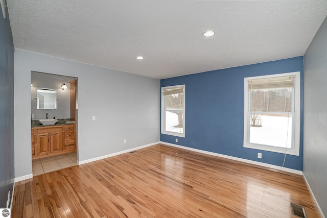 interior space featuring sink, light hardwood / wood-style floors, and a textured ceiling