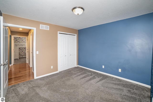 unfurnished bedroom featuring carpet floors, a textured ceiling, and a closet